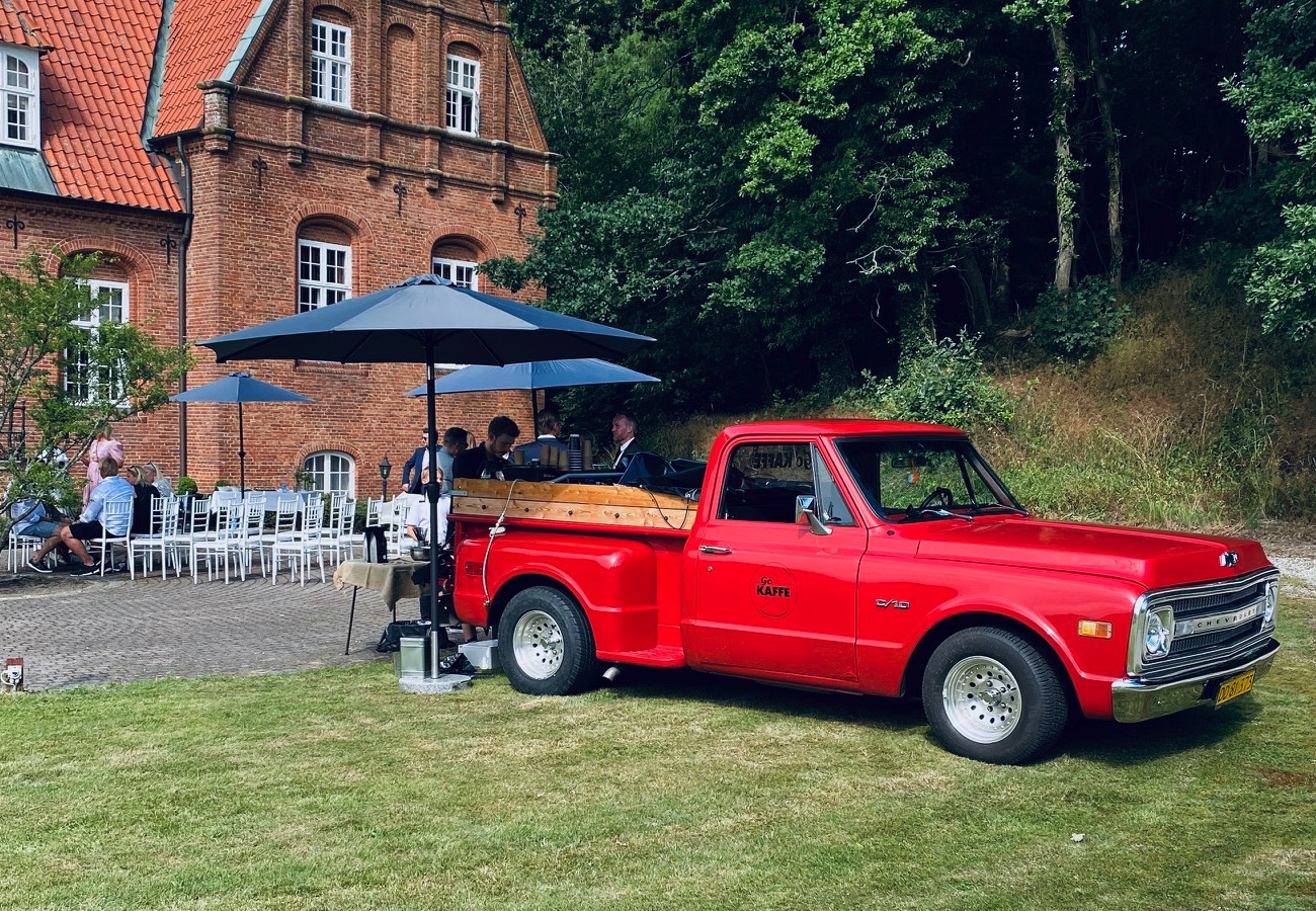 Rød kaffetruck foran gammel bygning i en skov